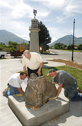 Richard Johnson, left, David Ashby and Clark Taylor place a rock from the Westman Islands in the plaza of the existing Icelandic memorial in Spanish Fork. Photo by Keith Johnson, Deseret Morning News