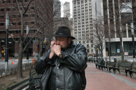The statue's creator, Dee Jay Bawden, blows a Mormon hymn on the harmonica. Photo by Carl Glassman